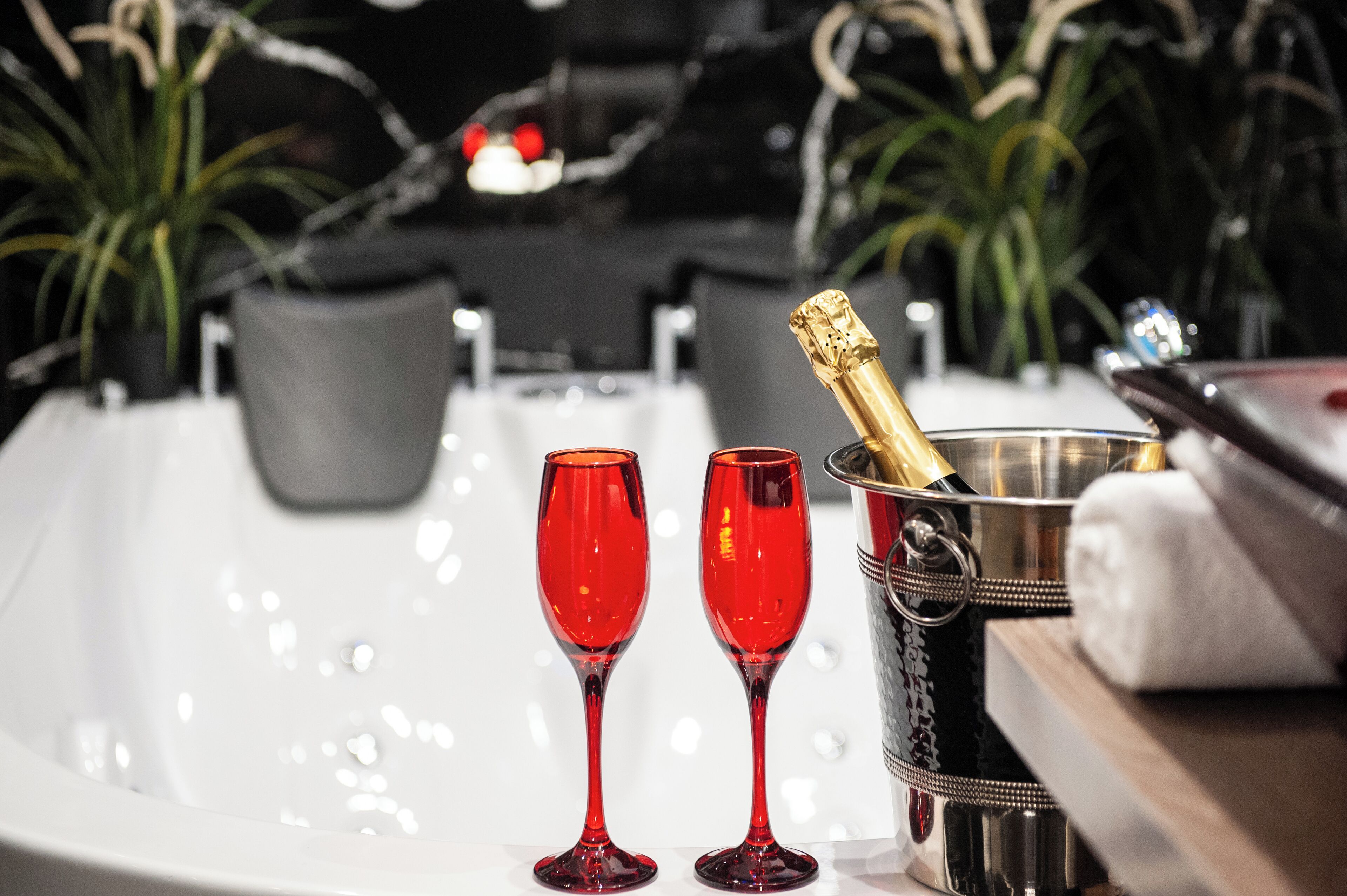 Une baignoire avec deux verres rouges et une bouteille de champagne.