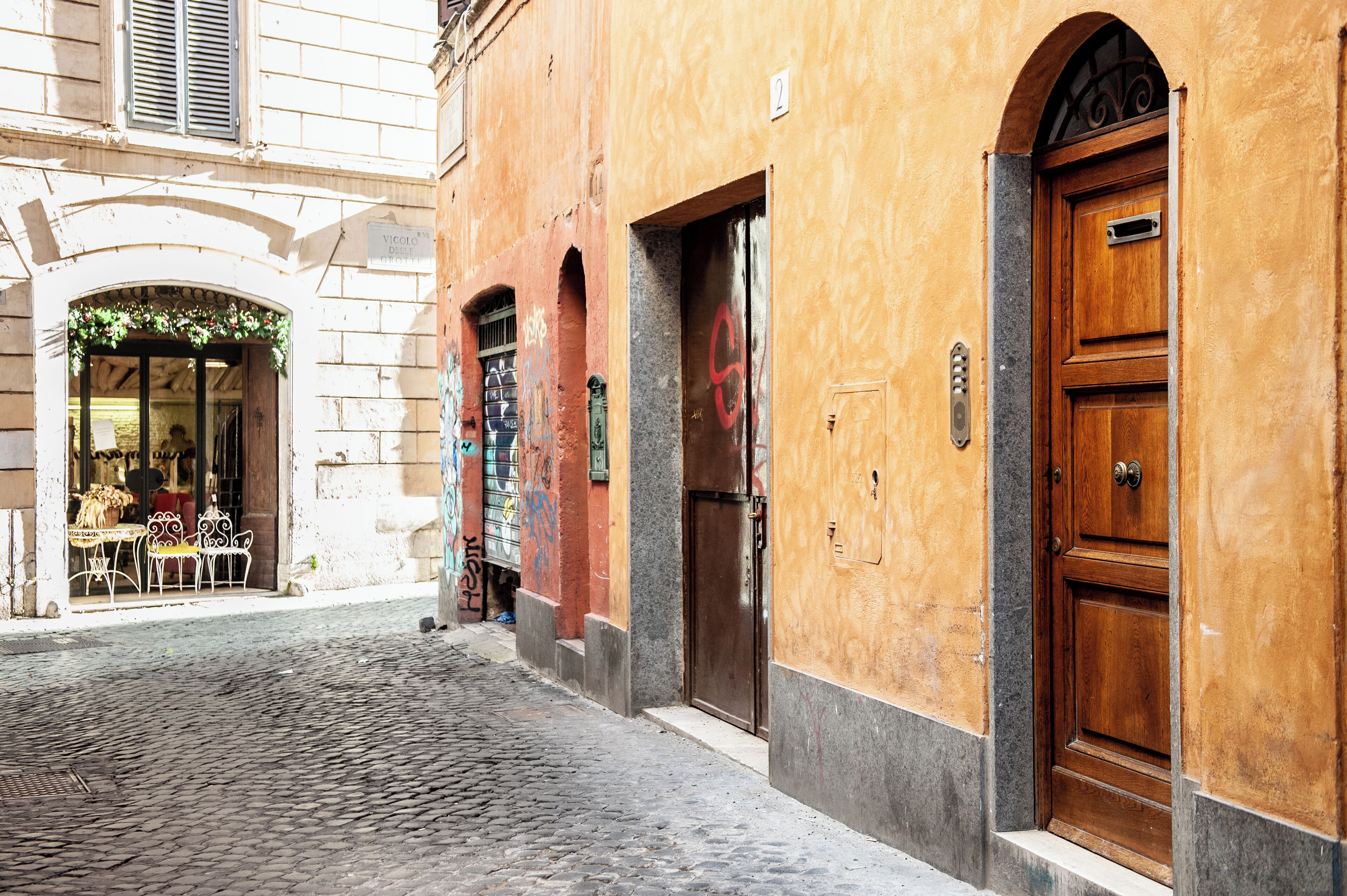 A cobblestone street with a building featuring a wooden door and a sign above it.