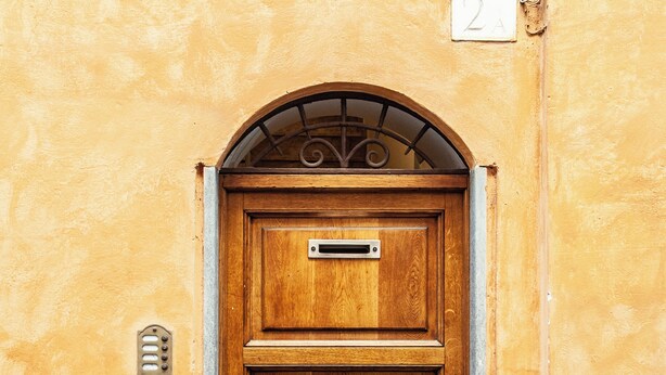 Una puerta de madera con un buzón metálico y el número '2A' encima.