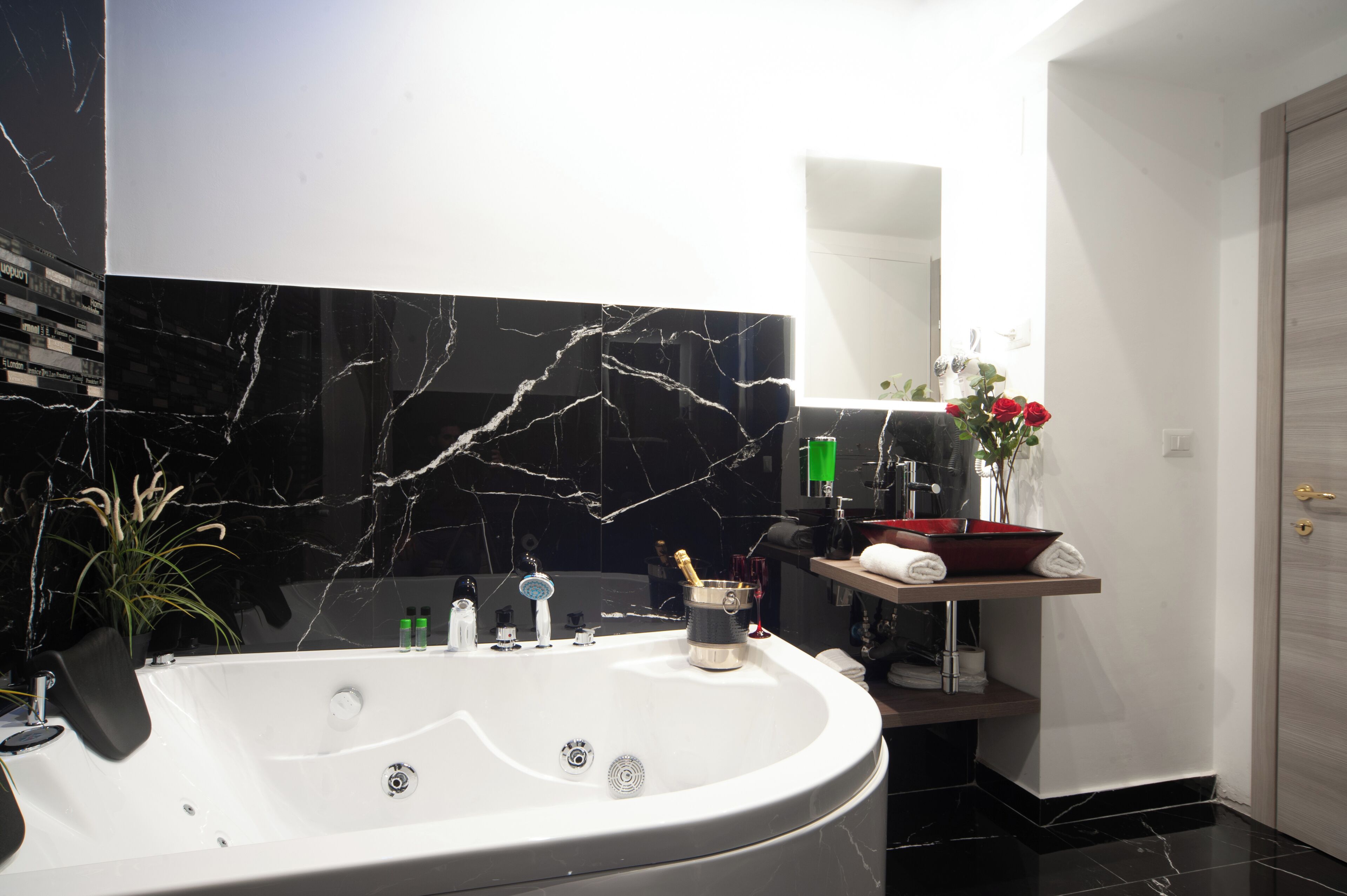 Een moderne badkamer met een groot bad, een wastafel met spiegel en een rode waskom.