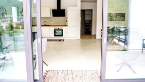 A modern kitchen with white cabinets, a black range hood, and a built-in oven.