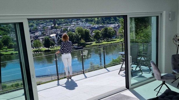 A modern room with a large glass window overlooking a river and a town.