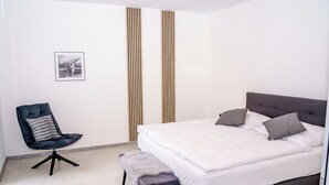 A modern bedroom with a large bed, a chair, and a rug.