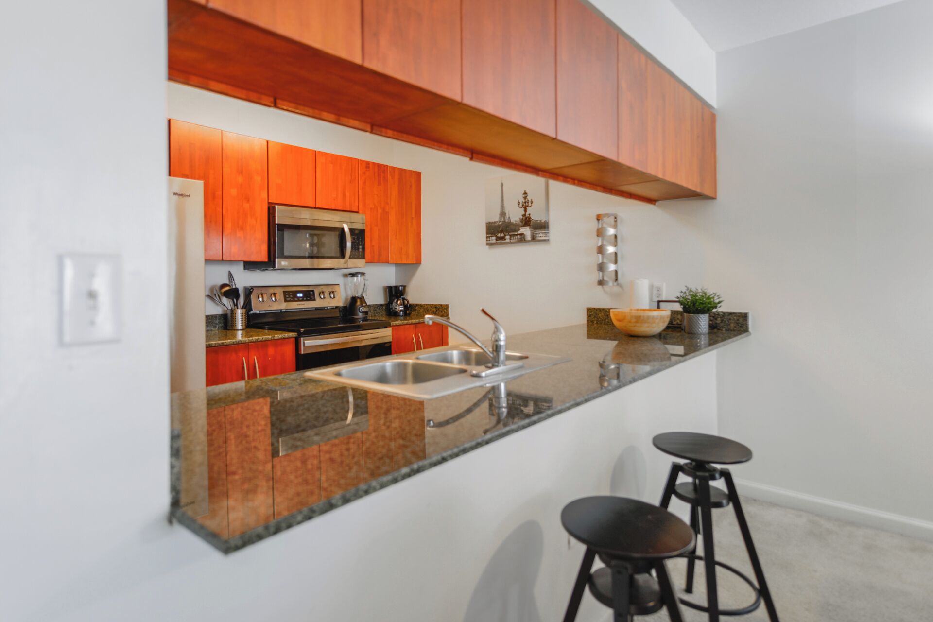 A modern kitchen with wooden cabinets, a stainless steel sink, and a granite countertop.