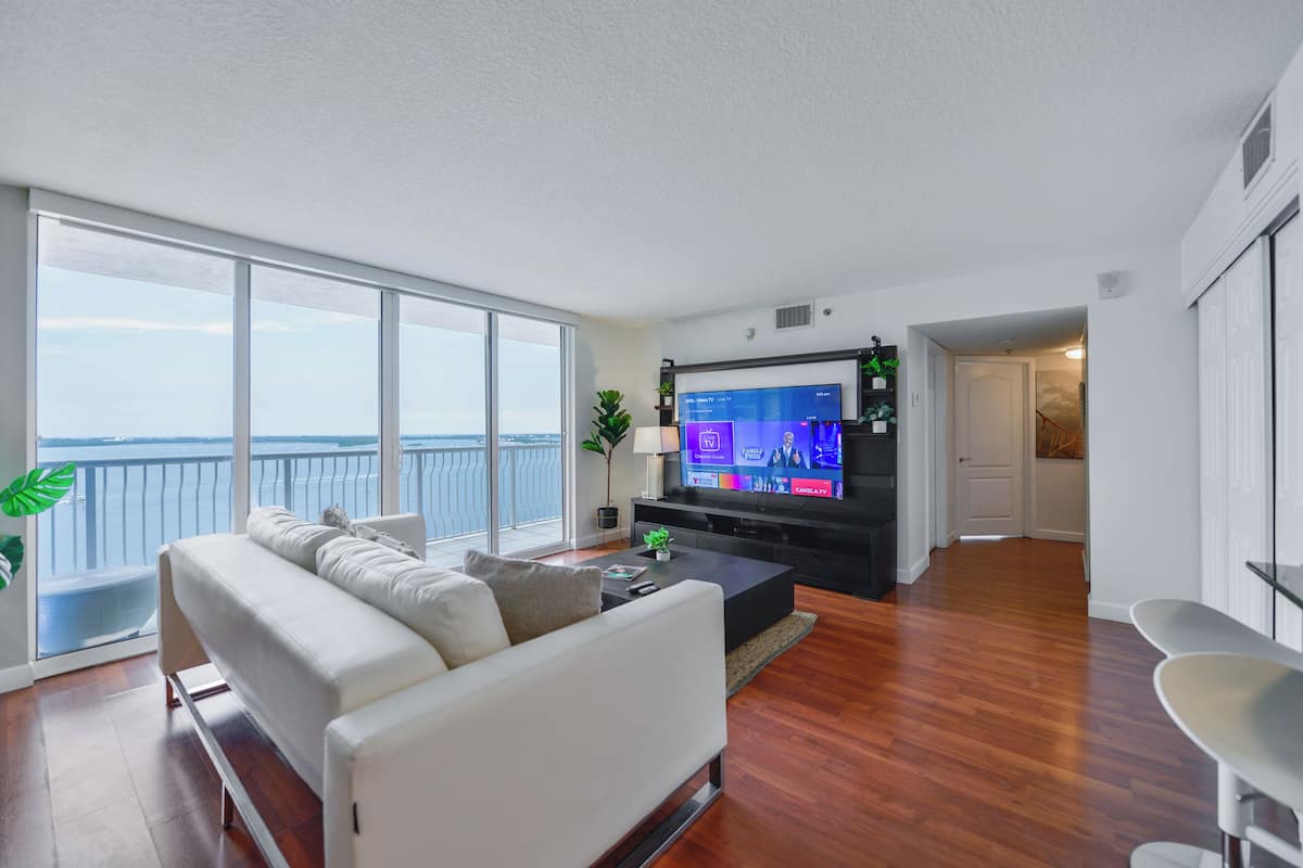 Una sala de estar moderna con un televisor grande, un sofá y vista al agua.