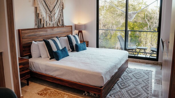 A bedroom with a large bed, a view of trees through a sliding door, and a hammock outside. - Elegant Loft in Tulum with Pool & Gym (Tulum)