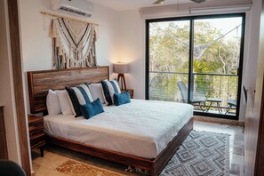 Un dormitorio con una cama grande, vistas a árboles a través de un ventanal corredero y una hamaca en el exterior.