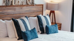 A neatly made bed with a wooden headboard, a macrame wall hanging, and a bedside lamp. - Elegant Loft in Tulum with Pool & Gym (Tulum)