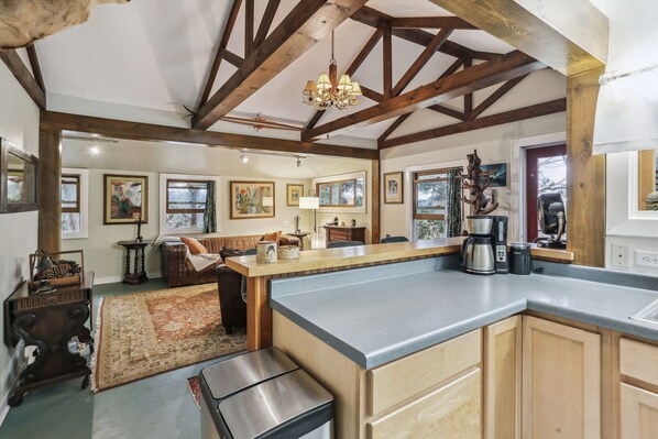 A spacious kitchen with a large island, wooden beams, and a chandelier.