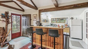 A kitchen with wooden beams, a red door, a bar area with stools, and a refrigerator. - Charming 1920's cottage in Afton up on bluff, river views! Swim, hike, explore! (Hastings)