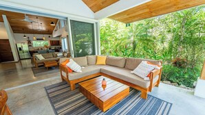 Una sala de estar moderna con un amplio sofá seccional, una mesa de centro de madera y vistas a un jardín exuberante.