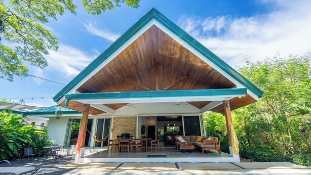 Una casa moderna con un porche cubierto, piscina y jardín.