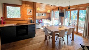 A wooden interior with a kitchen, dining area, and large windows.