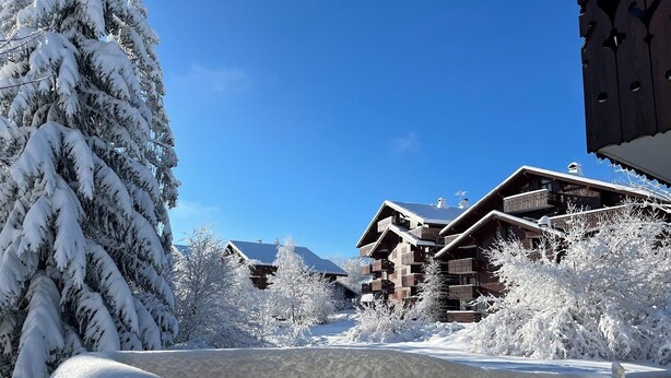 A snow-covered lodge with multiple balconies and a clear blue sky.