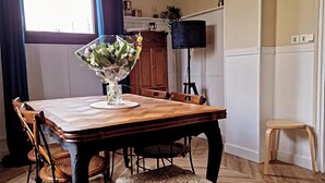 A dining area with a wooden table, chairs, and a bench. A bouquet of flowers is on the table. - Between station and Seine Renovated family home. Pets welcome! (Oissel)