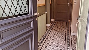 A hallway with patterned floor tiles, a decorative mirror, and a door with a glass panel. - Between station and Seine Renovated family home. Pets welcome! (Oissel)