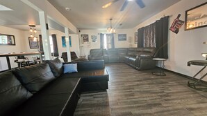 A spacious living room with a sectional sofa, a leather recliner, and a ceiling fan.