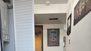 A hallway with a wooden floor, a black rug, and a Miller Lite poster on the wall.