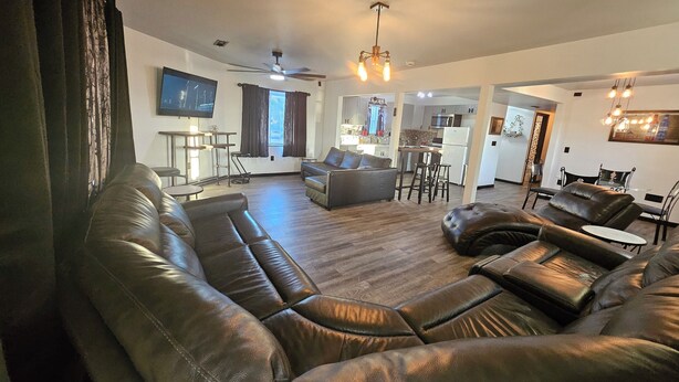A spacious living room with leather sofas, a dining area, and a kitchen in the background.