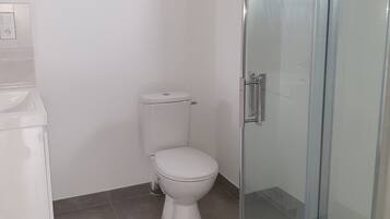 Een douche, handdoeken, zeep, toiletpapier