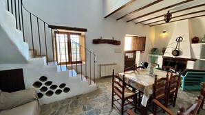 Un intérieur rustique avec un escalier en pierre, une table à manger en bois et une cheminée.