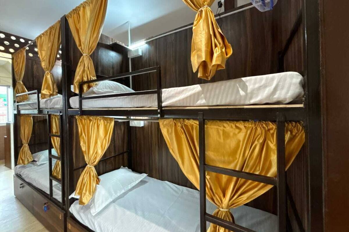 Ein Schlafraum mit Etagenbetten, goldenen Vorhängen und Deckenventilator.