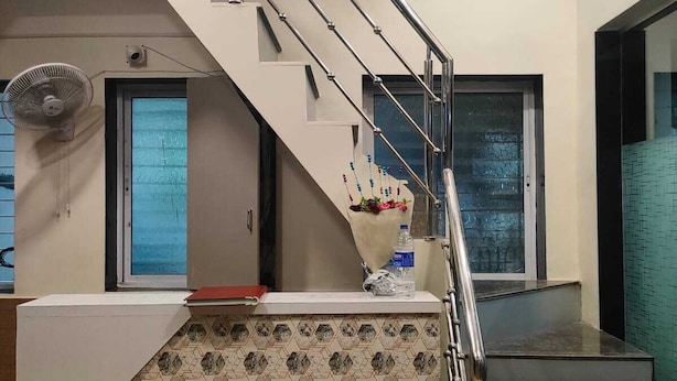 Una escalera moderna con barandilla de metal, un ventilador en la pared y un revestimiento de azulejos con diseño.