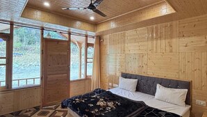 Ein Schlafzimmer einer Holzhütte mit Bett, Deckenventilator und großen Fenstern.
