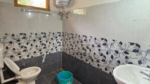 Ein Badezimmer mit Toilette, Waschbecken und einem Fenster über der Toilette.