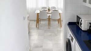 Une cuisine moderne équipée d’un lave-linge, d’un four à micro-ondes et d’un plan de travail bleu.