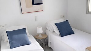 Une chambre d’hôtel avec deux lits simples, une petite table de chevet avec une lampe et une œuvre d’art abstraite accrochée au mur.