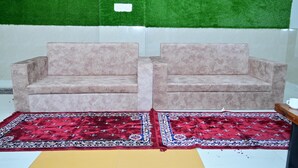 Two beige sofas with a red patterned rug in front. - Hotel Red Inn (Jodhpur)