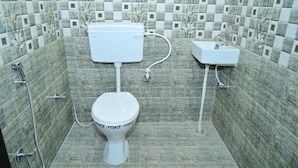 A bathroom with a toilet, bidet, and sink, tiled with a floral pattern. - Hotel Red Inn (Jodhpur)