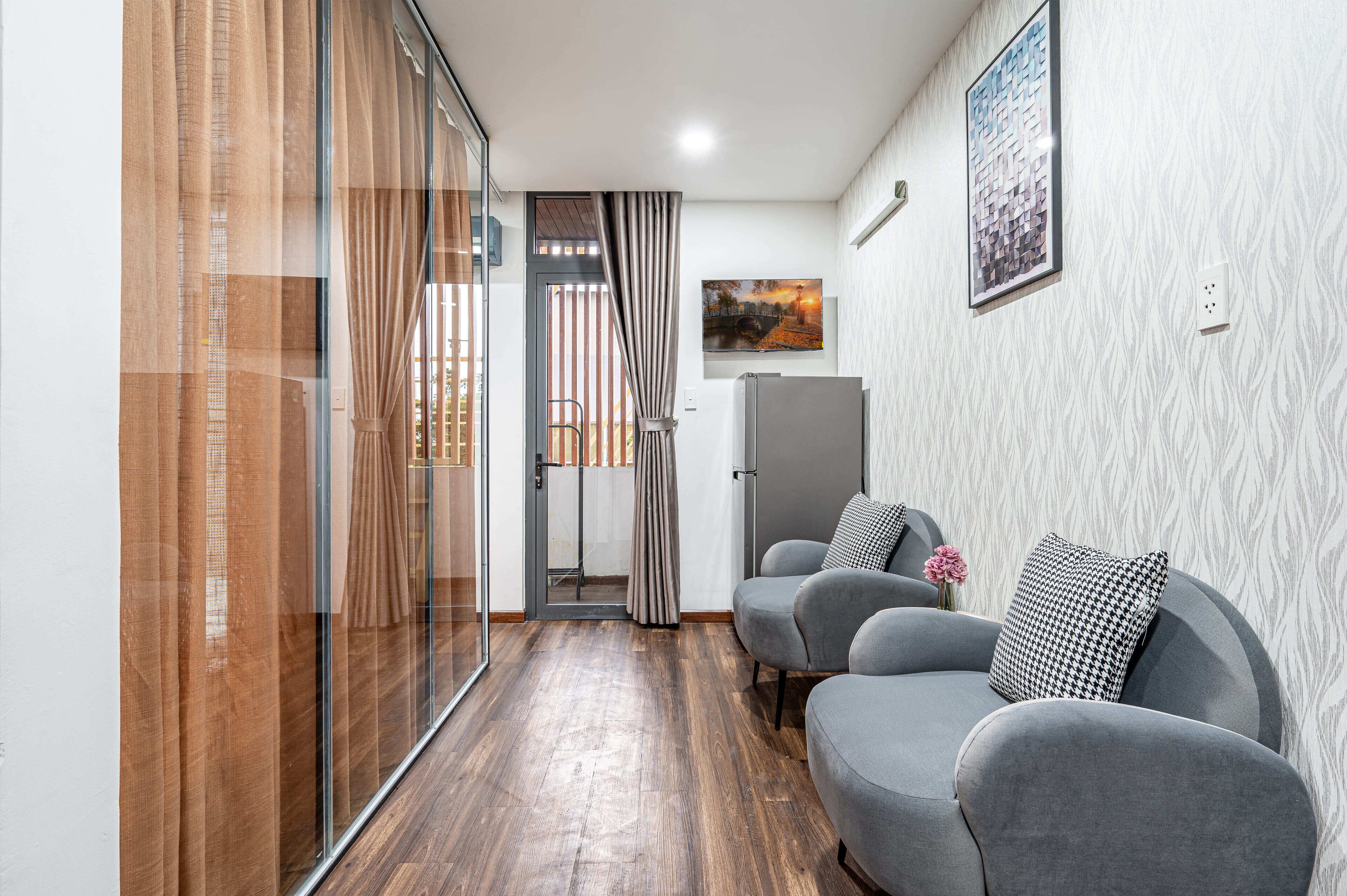 Un salon moderne avec un canapé gris, une porte vitrée donnant sur un balcon et un tableau encadré accroché au mur.