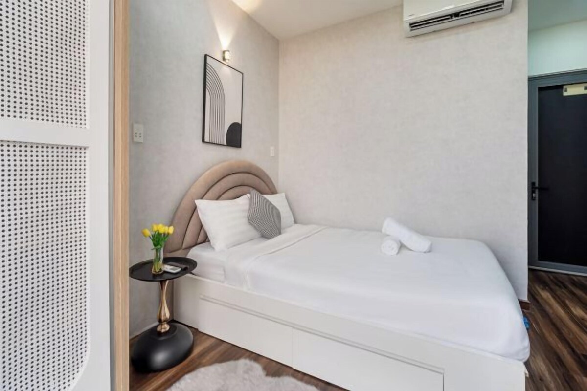 Quarto bem organizado com cama, mesa de cabeceira e ar condicionado fixado na parede.