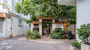 A narrow street with a small shop entrance, potted plants, and a motorcycle parked outside. - Lalala Inn Hotel (Ho Chi Minh City)