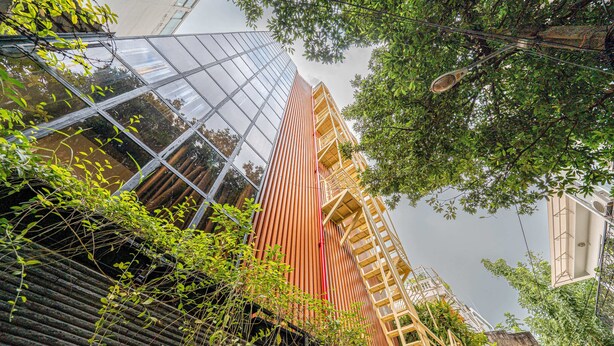 A modern building with a glass facade and a wooden structure with a red vertical stripe. - Lalala Inn Hotel (Ho Chi Minh City)