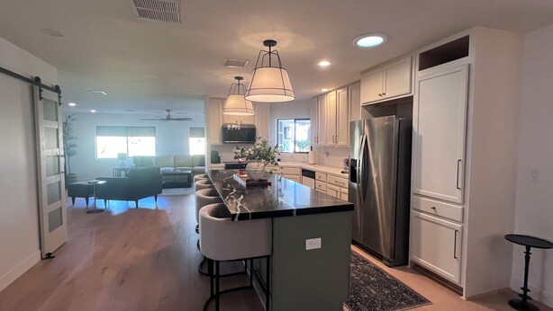 A modern kitchen with a central island, stainless steel appliances, and pendant lighting.