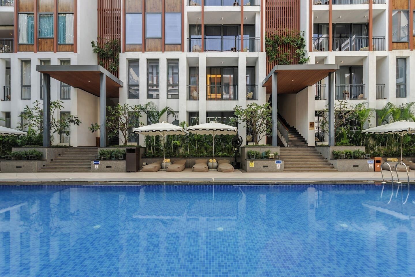 Un hôtel moderne doté d’une piscine, d’un espace extérieur aménagé et d’un escalier menant aux étages supérieurs.
