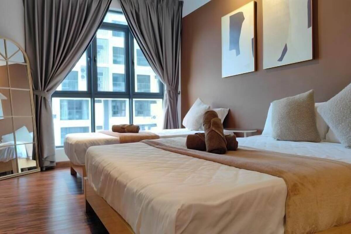 A hotel room with two beds, a large window, and a view of the cityscape.