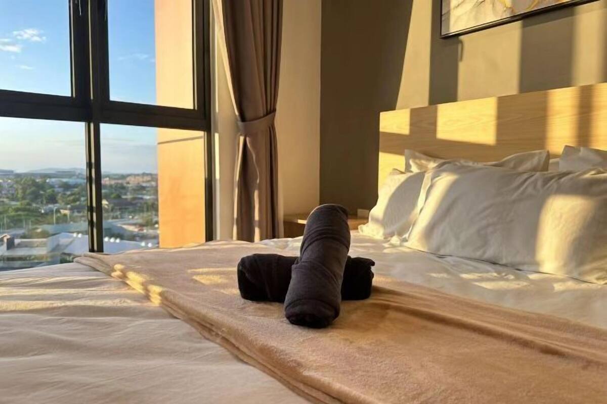 A hotel room with a bed, a window with curtains, and a view of a cityscape.