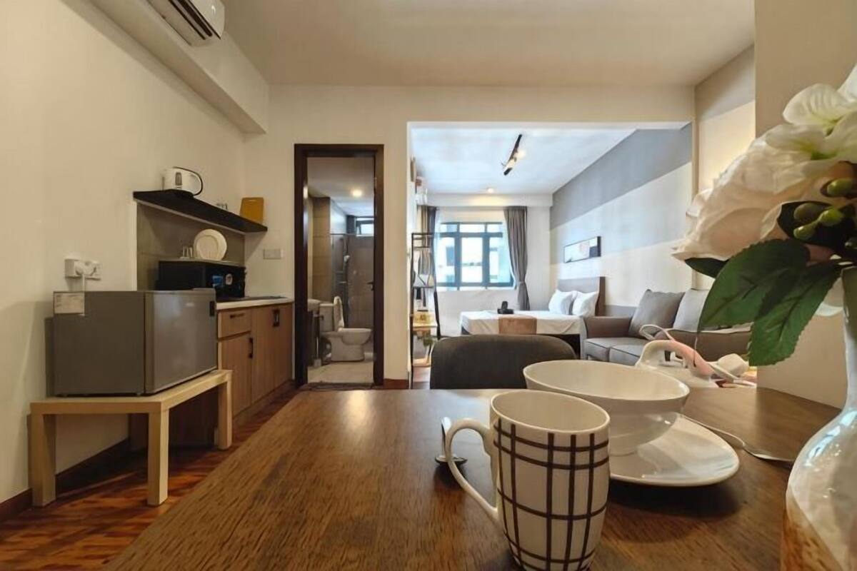 A compact hotel room with a kitchenette, a dining area, a bed, and a bathroom visible through an open door.