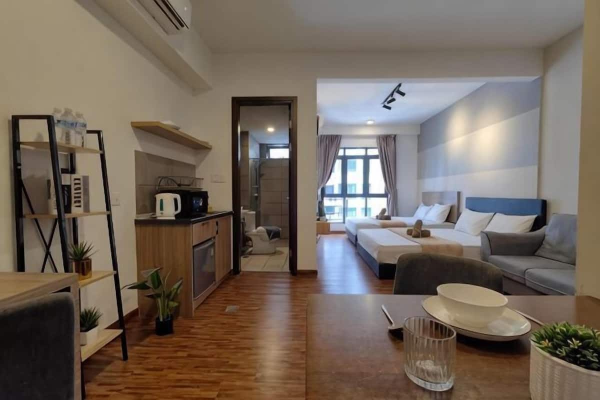 A modern hotel room with a kitchenette, a dining area, a sofa, and a bed.
