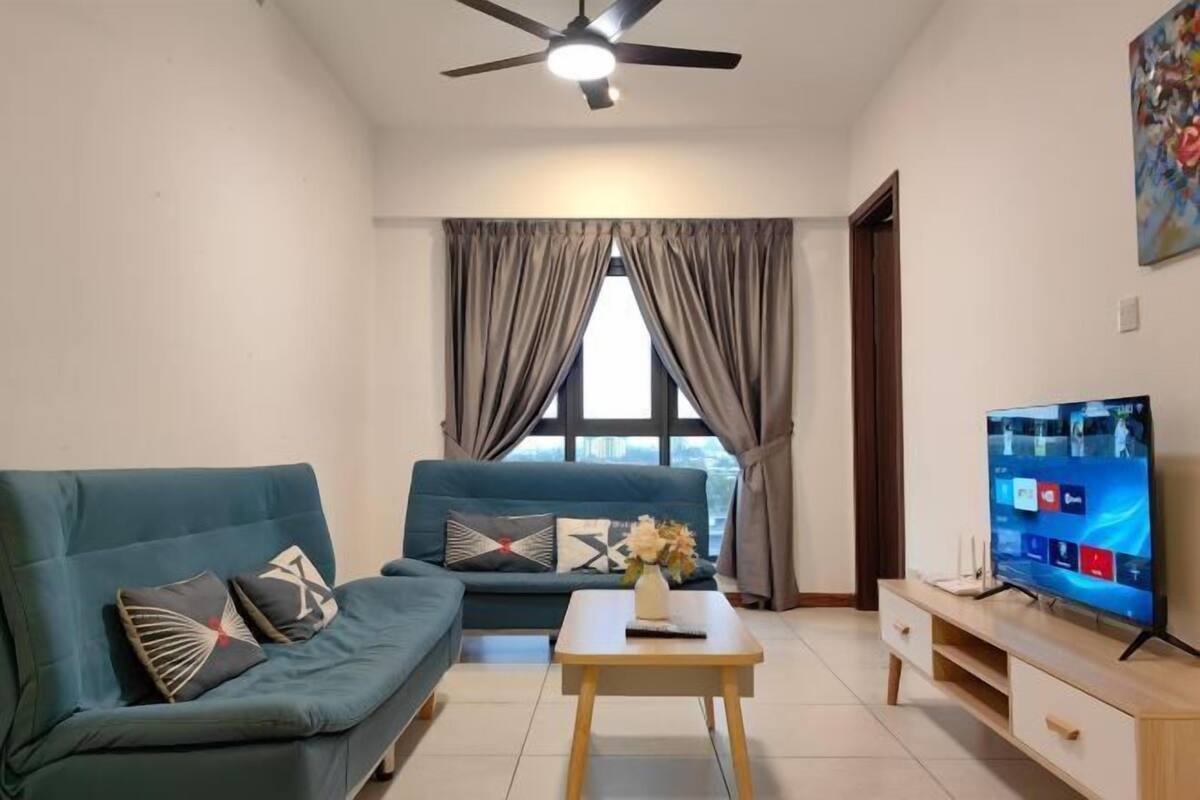 A living room with a sofa, a coffee table, a TV, and a ceiling fan.