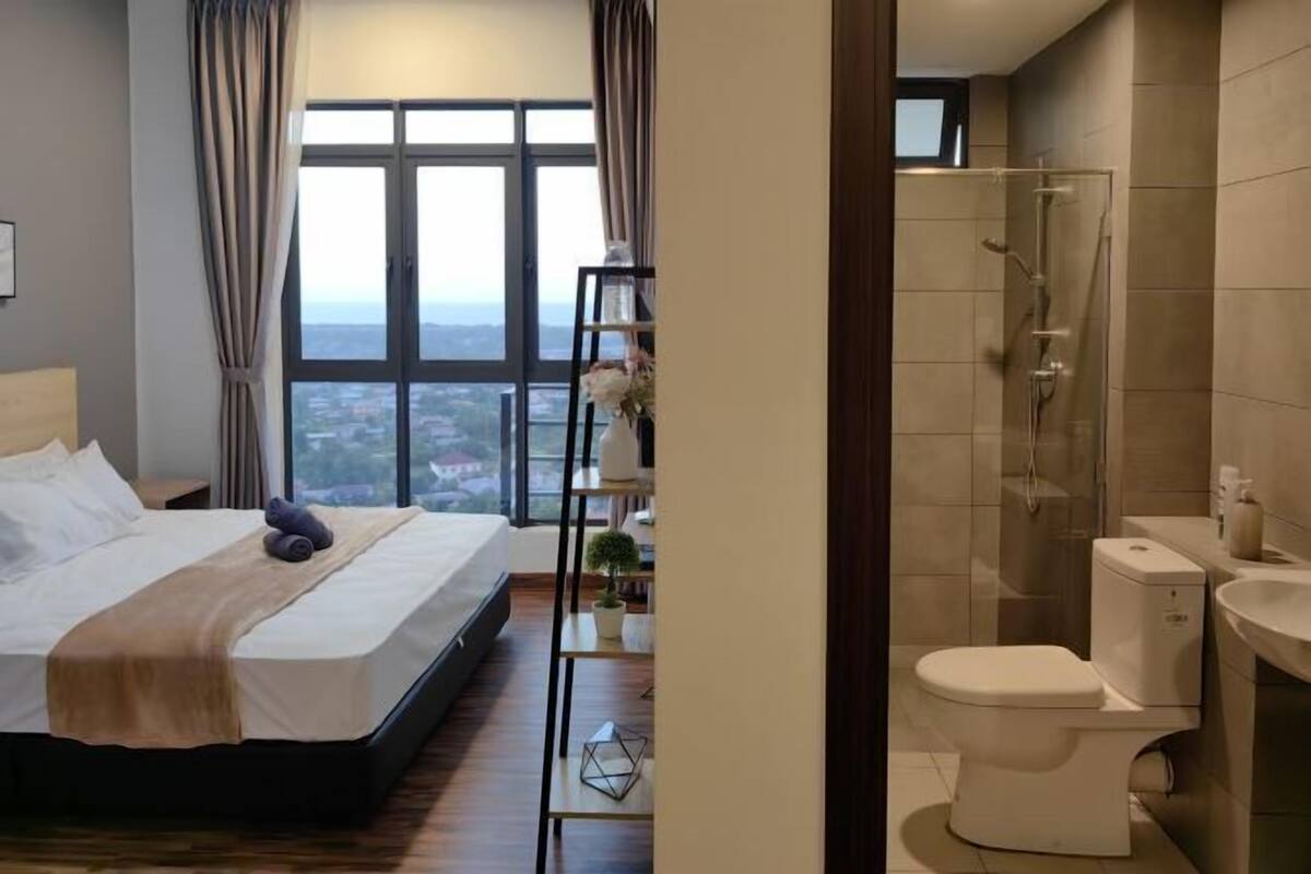 A bedroom with a large window, a bed, a bedside table, and a nightstand.