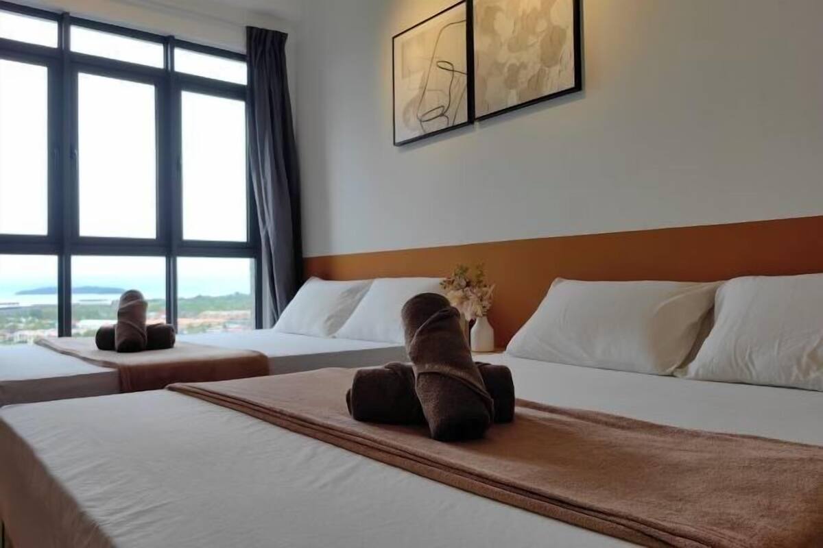 A hotel room with two beds, a large window, and artwork on the wall.
