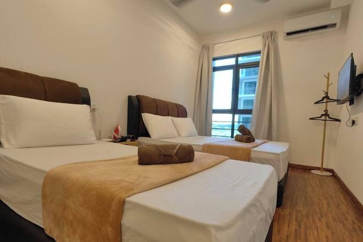 A hotel room with two beds, a TV, and a window with curtains.