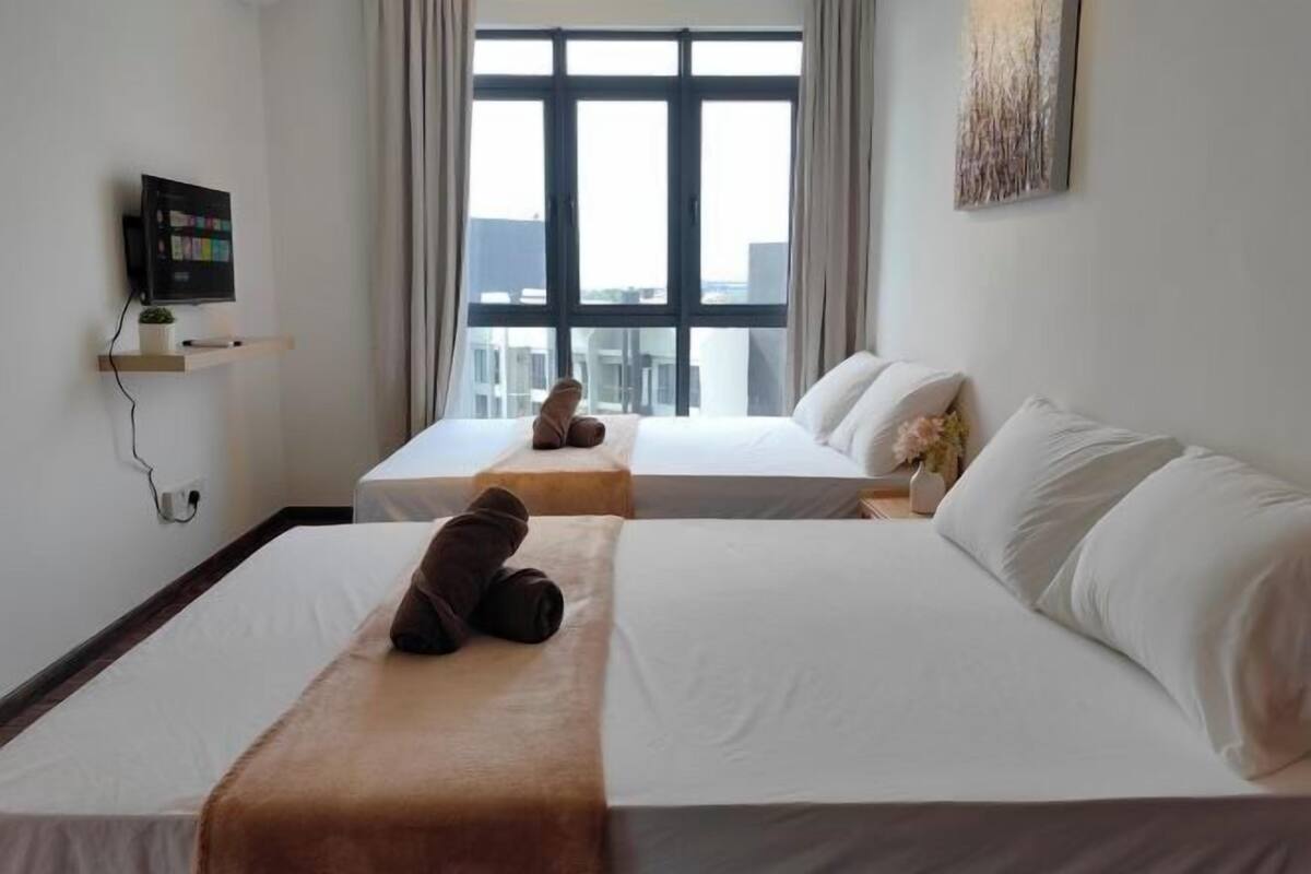A hotel room with two beds, a TV, a window with curtains, and a painting on the wall.