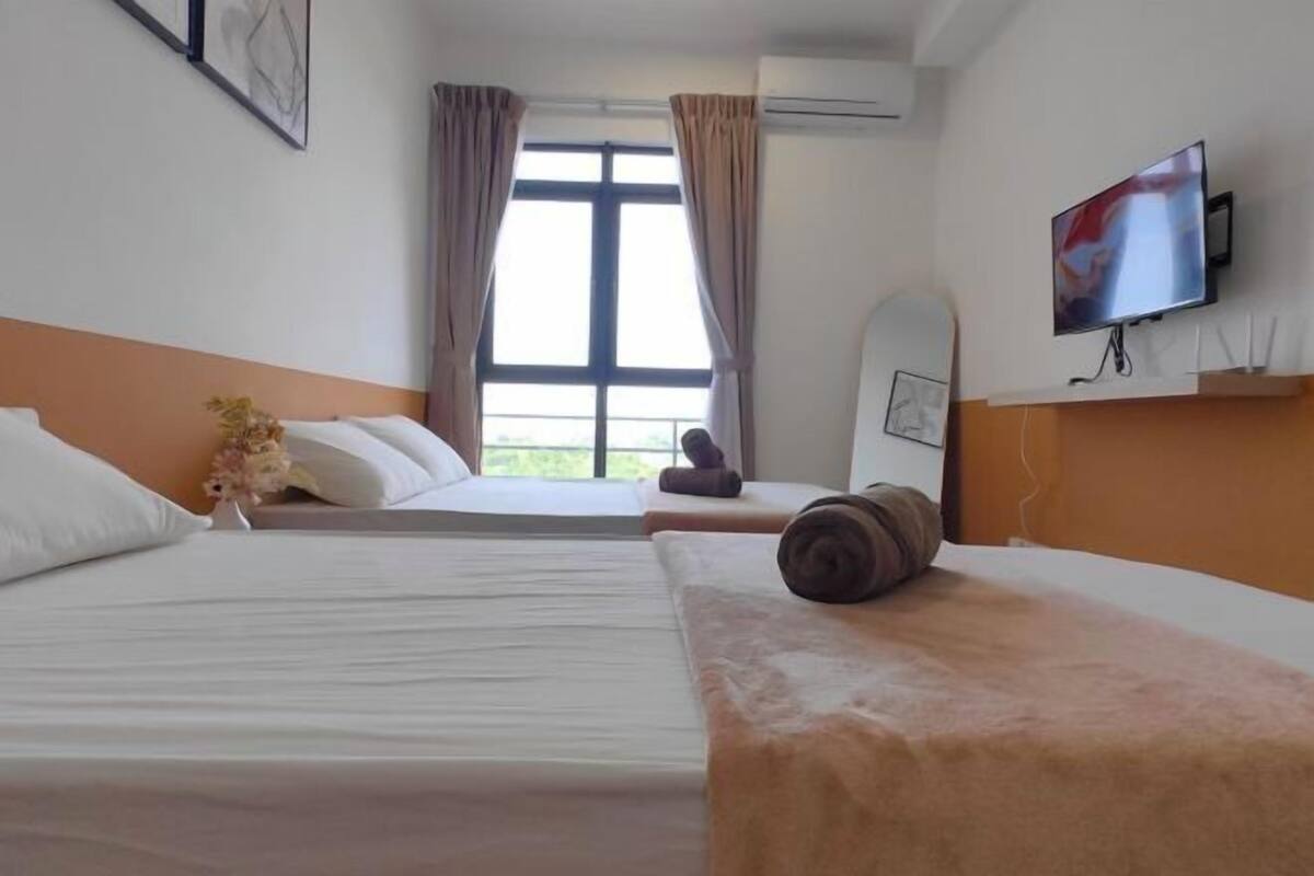 A hotel room with two beds, a TV, and a window with curtains.