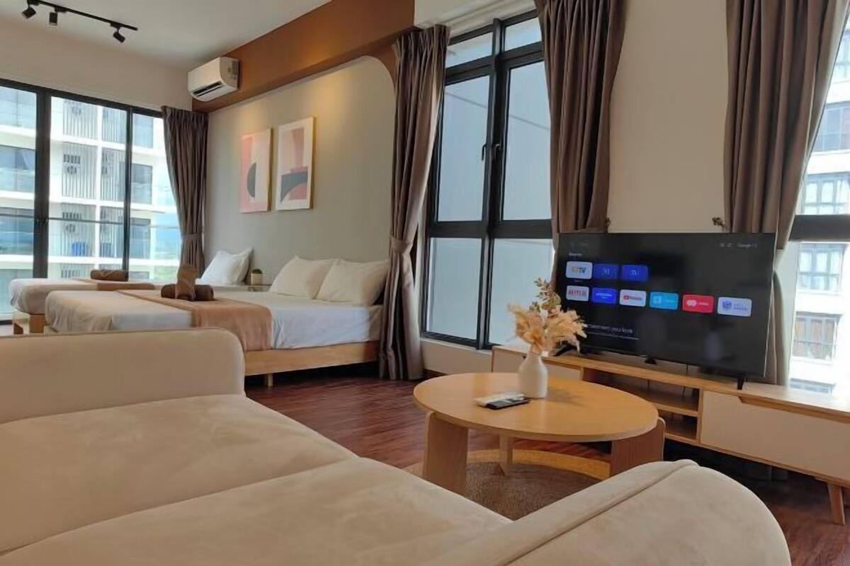 A hotel room with a bed, a sofa, a TV, and a window with curtains.